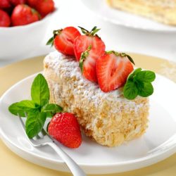 A slice of Napoleon cake with strawberries and mint. Layer cake with cream, closeup.