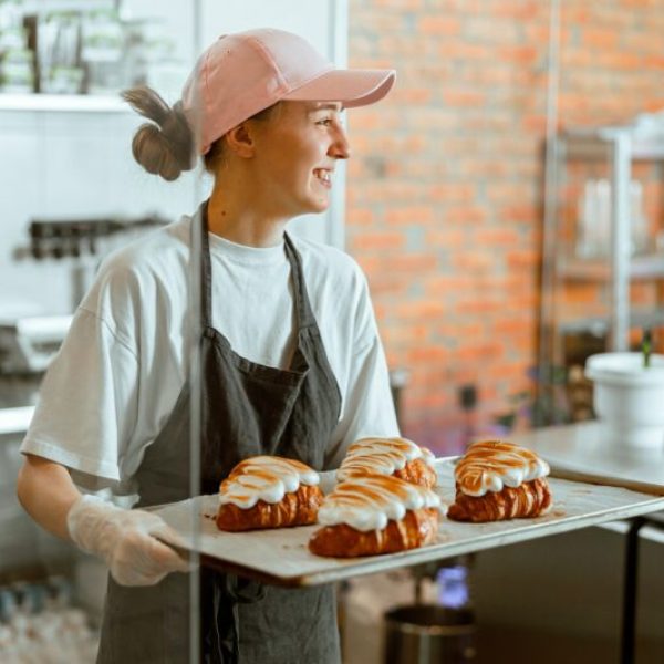 Pretty woman baker holds beautiful croissants with burnt albumenous cream in shop